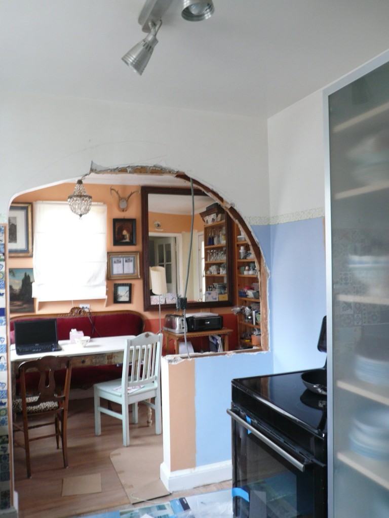 Half-demolished kitchen partition wall with hanging electrical wire